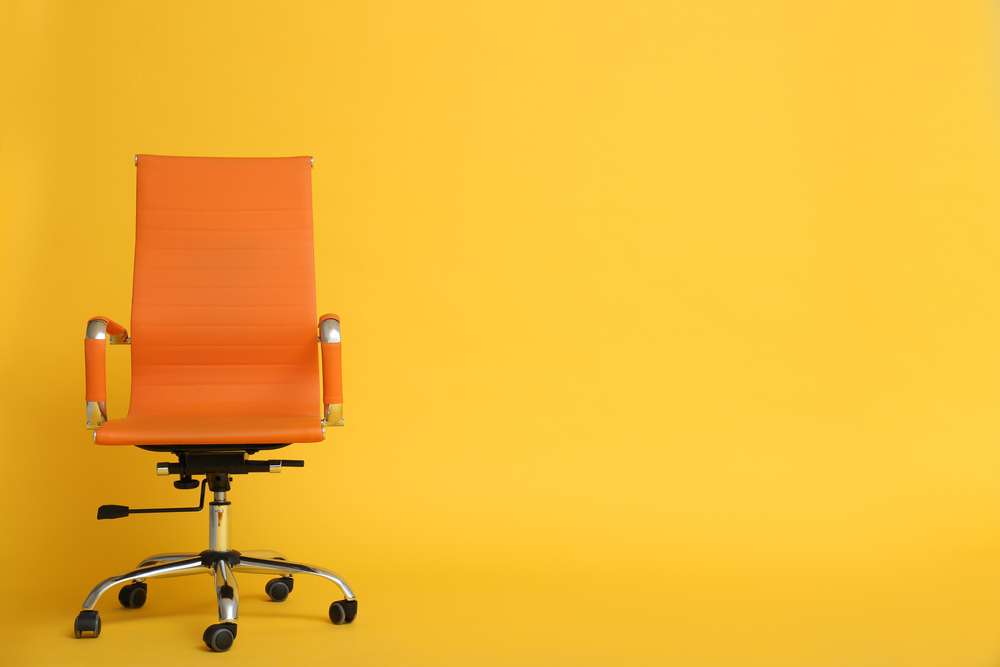 Oranžen pisarniški stol in rumena stena.