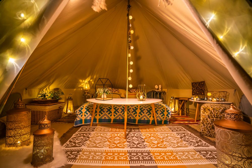 Pogled na razkošen glamping šotor, poln ambientalnih luči, pisanih preprog in blazin.