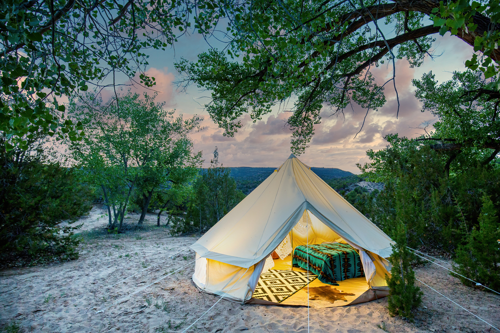Glamping šotor z mehko posteljo in preprogo nudi udobje v objemu narave.